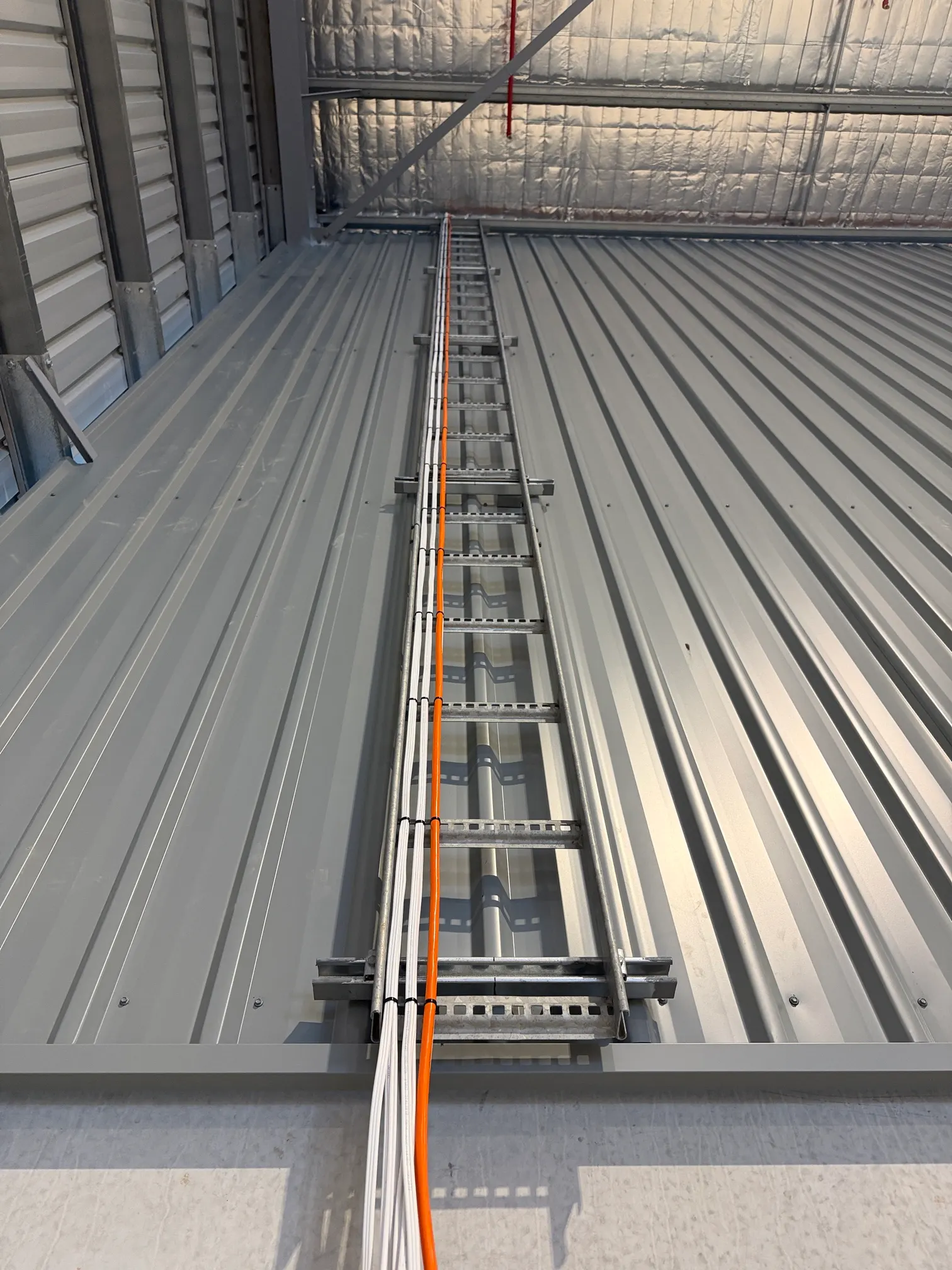 Cable ladder carrying cables across a warehouse ceiling